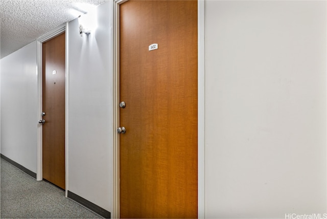 hall with light carpet and a textured ceiling