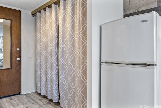 interior space featuring light hardwood / wood-style floors, a textured ceiling, and white refrigerator