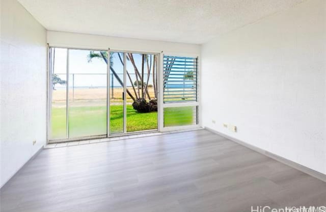 unfurnished room with wood-type flooring and a textured ceiling