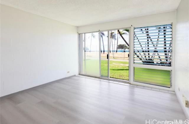 spare room with a textured ceiling and light wood-type flooring