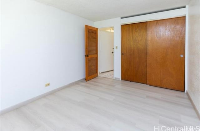 unfurnished bedroom with light hardwood / wood-style flooring and a closet