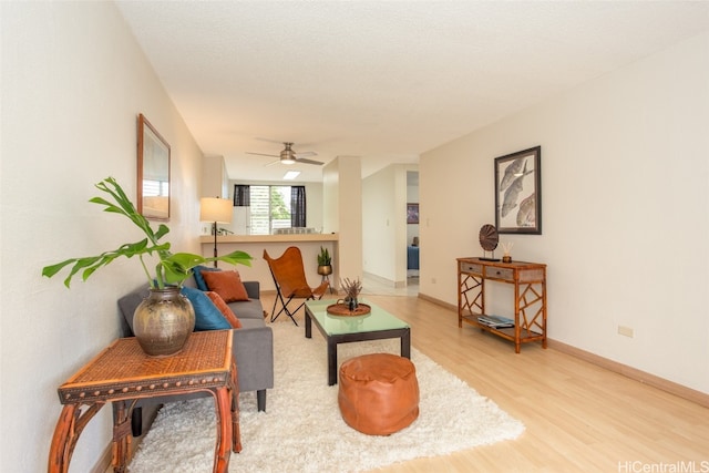 living room featuring light hardwood / wood-style floors, a textured ceiling, and ceiling fan