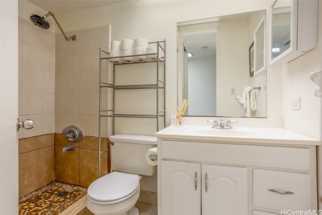 bathroom with vanity, a tile shower, toilet, and tile patterned flooring