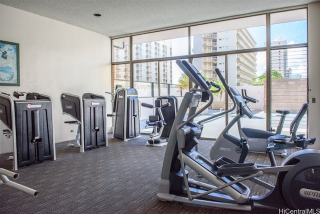 workout area with a wall of windows, a textured ceiling, and dark colored carpet