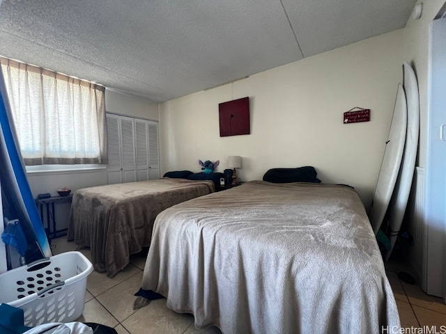 bedroom featuring a closet, a textured ceiling, and light tile patterned floors