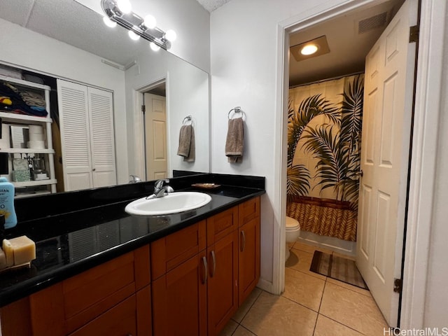 bathroom featuring a textured ceiling, walk in shower, toilet, vanity, and tile patterned flooring