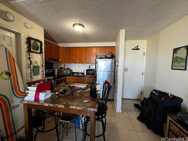 kitchen featuring light tile patterned flooring, appliances with stainless steel finishes, and a textured ceiling