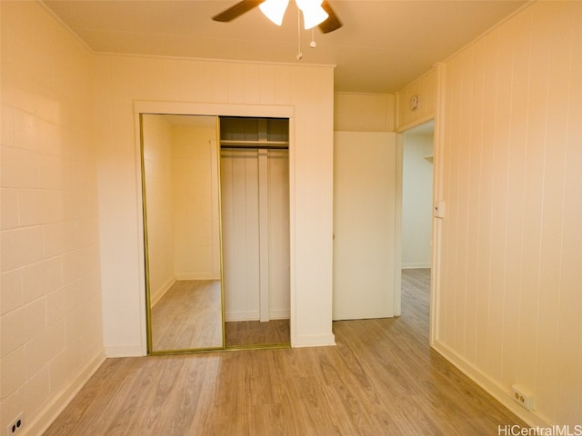 unfurnished bedroom with a closet, ceiling fan, crown molding, and light wood-type flooring