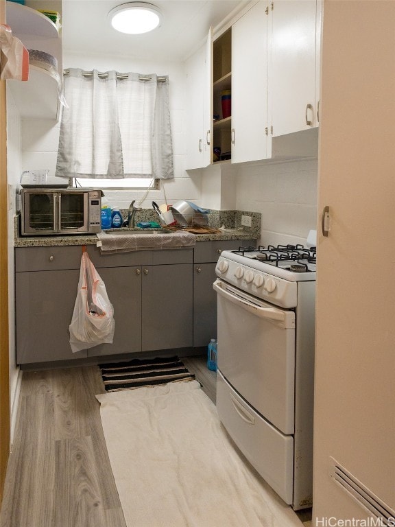 kitchen with light hardwood / wood-style flooring, white cabinetry, range with gas stovetop, and gray cabinetry