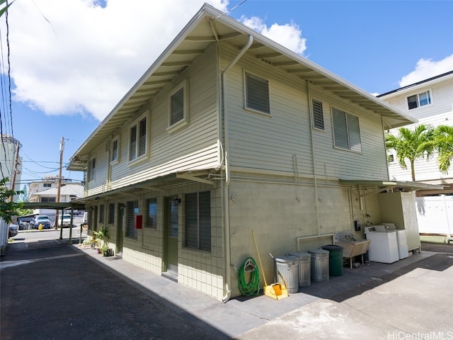 view of property exterior with washing machine and dryer and a carport