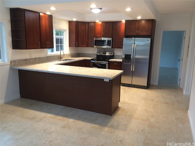 kitchen with sink, appliances with stainless steel finishes, kitchen peninsula, and a tray ceiling