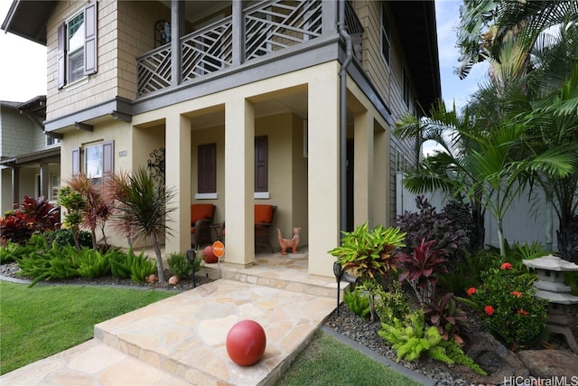 doorway to property featuring a patio, a lawn, and a balcony