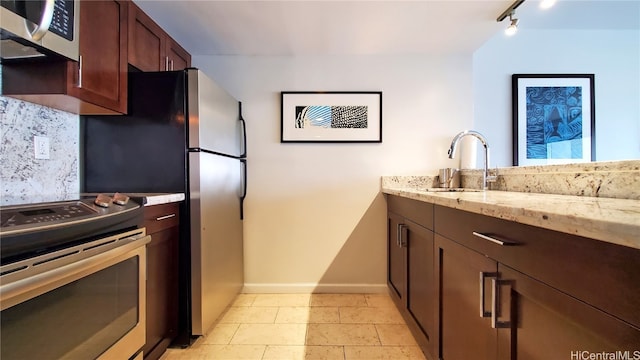 kitchen featuring light stone countertops, sink, appliances with stainless steel finishes, and track lighting