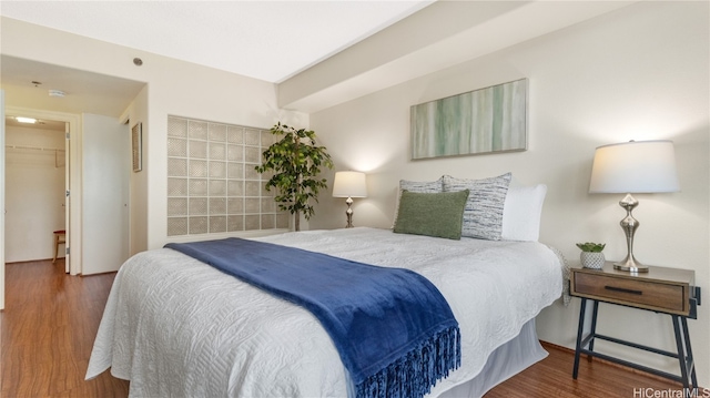 bedroom with a closet, a walk in closet, and dark hardwood / wood-style floors