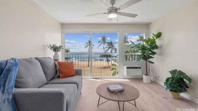 living room featuring a wall mounted AC, a healthy amount of sunlight, wood-type flooring, and a water view