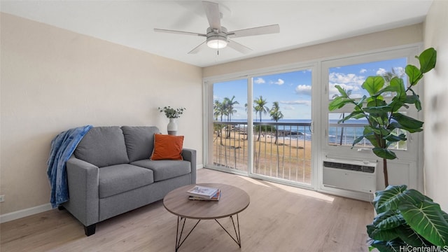 living area with light hardwood / wood-style flooring, an AC wall unit, a water view, and ceiling fan