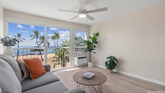 living area featuring light hardwood / wood-style flooring, a wall mounted AC, a water view, and ceiling fan