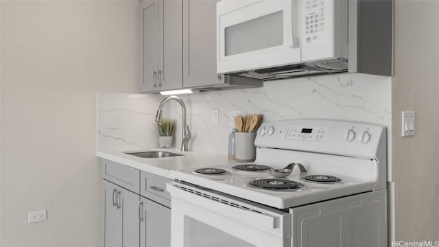 kitchen with gray cabinets, sink, white appliances, and tasteful backsplash