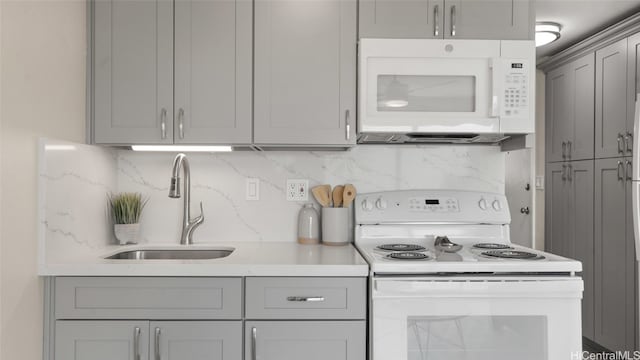 kitchen with white appliances, backsplash, sink, and gray cabinets