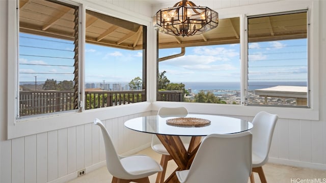 dining area with a chandelier, a water view, and wood walls