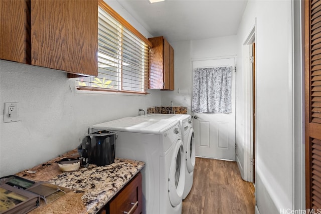 laundry room with light hardwood / wood-style floors, washing machine and dryer, and cabinets