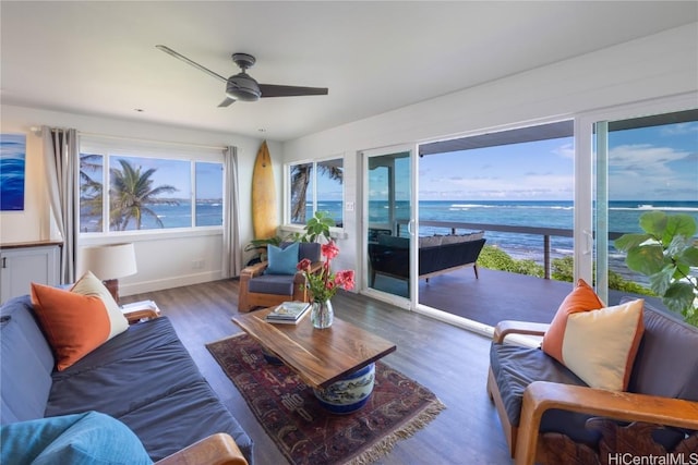 living room featuring dark hardwood / wood-style flooring, ceiling fan, and a water view