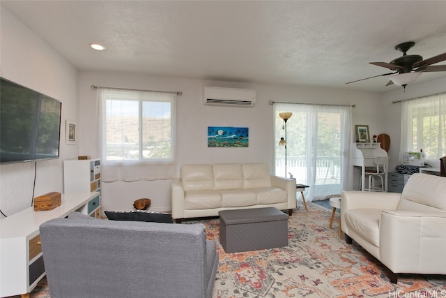 living room with ceiling fan, plenty of natural light, and a wall unit AC