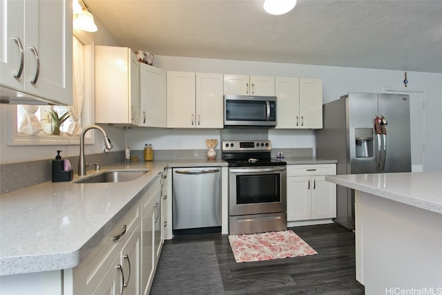 kitchen with dark hardwood / wood-style floors, sink, white cabinetry, appliances with stainless steel finishes, and light stone counters