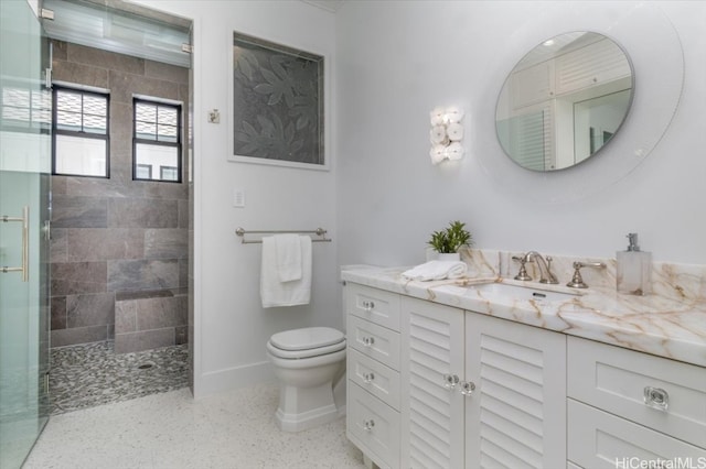 bathroom with vanity, toilet, and tiled shower