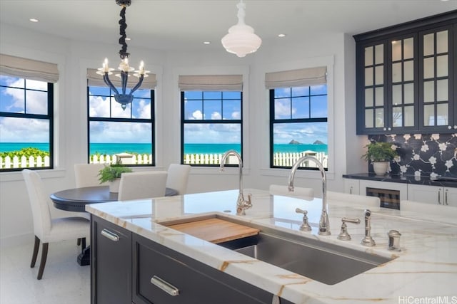 kitchen with plenty of natural light, decorative backsplash, hanging light fixtures, and a water view