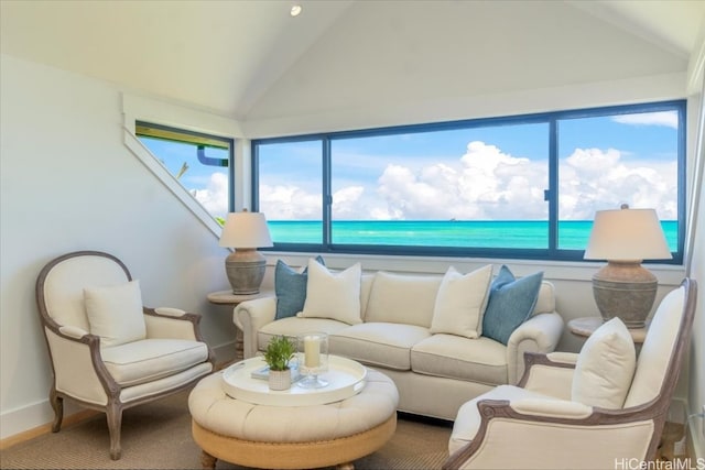 living room featuring plenty of natural light, lofted ceiling, a view of the beach, and a water view