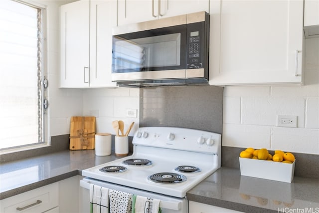 kitchen featuring white range with electric stovetop, white cabinets, and a healthy amount of sunlight