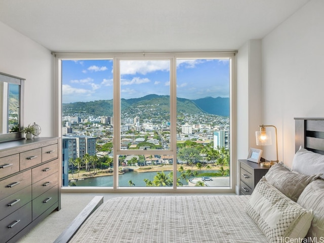 bedroom featuring light carpet, multiple windows, a water and mountain view, and floor to ceiling windows