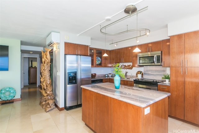 kitchen with light stone counters, stainless steel appliances, sink, decorative light fixtures, and a center island