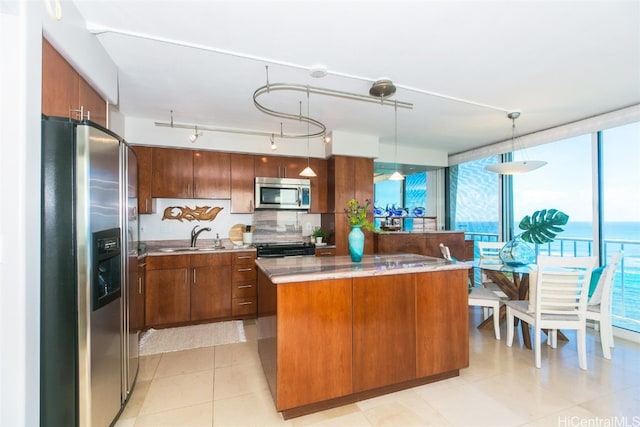 kitchen with tasteful backsplash, sink, a kitchen island, hanging light fixtures, and stainless steel appliances