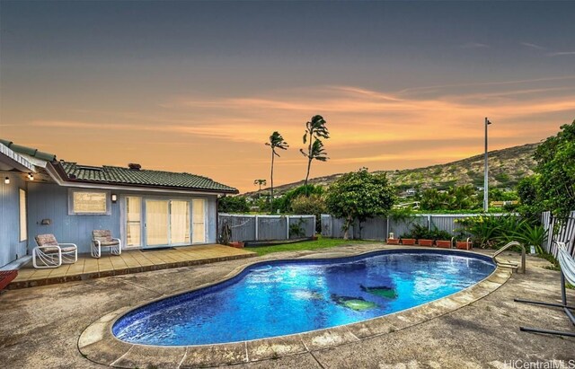 pool at dusk with a patio area