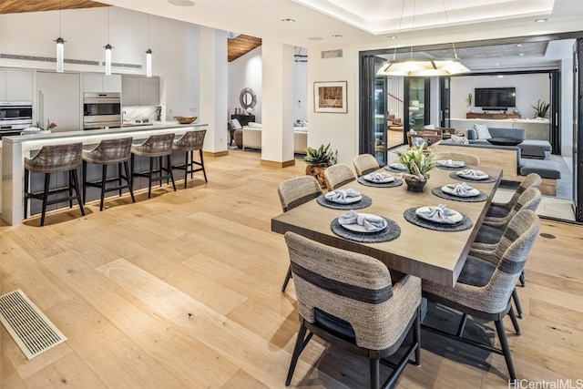 dining room with light hardwood / wood-style floors and a tray ceiling