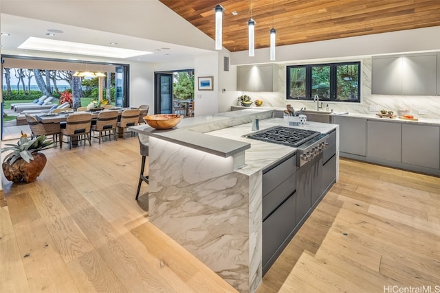 kitchen featuring lofted ceiling, gray cabinetry, wooden ceiling, a wealth of natural light, and stainless steel gas stovetop