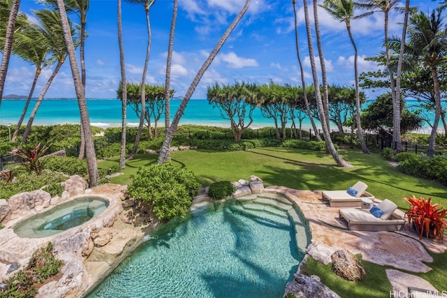 view of pool with a water view, an in ground hot tub, and a lawn