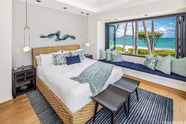 bedroom with a water view and hardwood / wood-style flooring