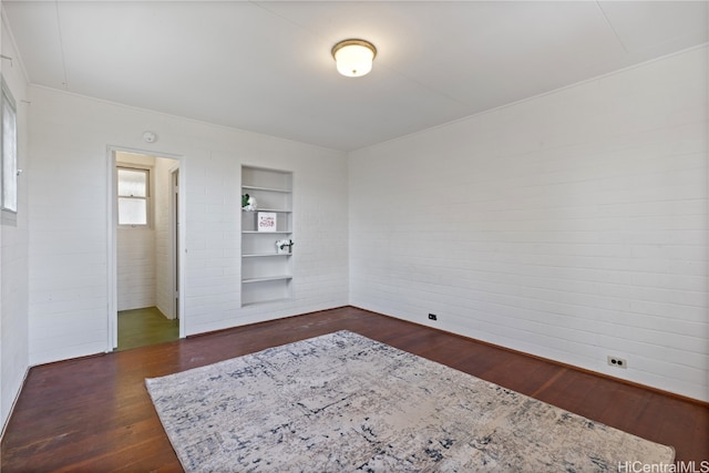 unfurnished room with built in shelves and dark hardwood / wood-style flooring