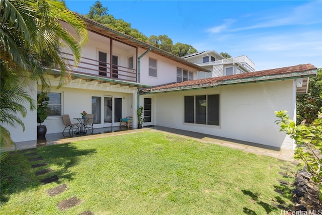 back of property with a lawn, a balcony, and a patio area