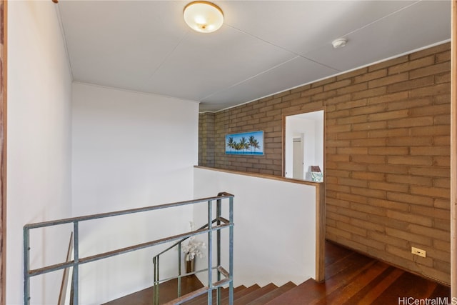 hallway with brick wall and dark hardwood / wood-style floors