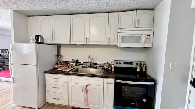 1655 Makaloa St Unit 1009, Honolulu, HI 96814 - kitchen featuring dark countertops, a sink, white appliances, a textured ceiling, and white cabinetry