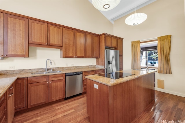 kitchen with sink, light stone counters, decorative light fixtures, a center island, and appliances with stainless steel finishes