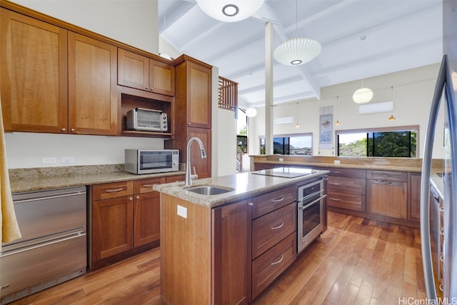 kitchen featuring pendant lighting, sink, a kitchen island with sink, light stone counters, and stainless steel appliances