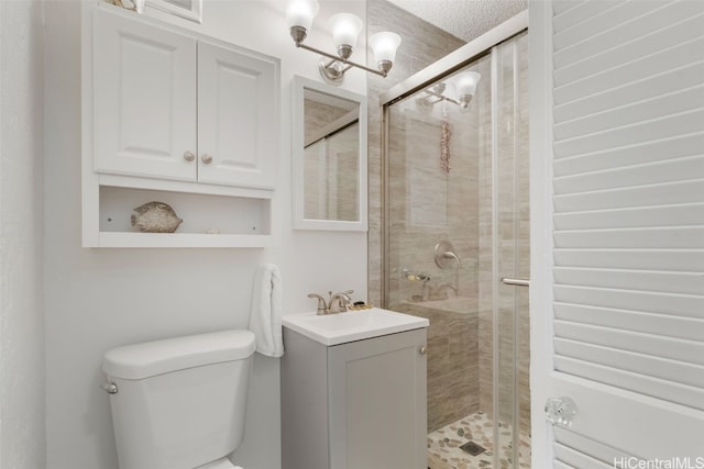 bathroom with vanity, toilet, a textured ceiling, and an enclosed shower