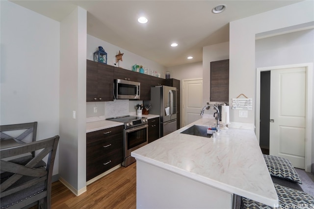 kitchen featuring sink, kitchen peninsula, stainless steel appliances, dark brown cabinetry, and dark wood-type flooring