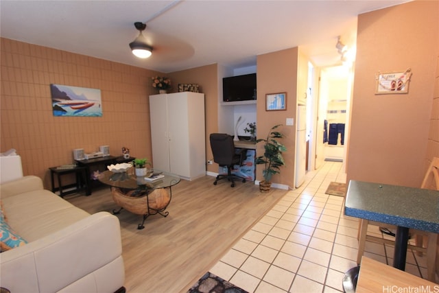 living room featuring wood-type flooring, tile walls, and ceiling fan