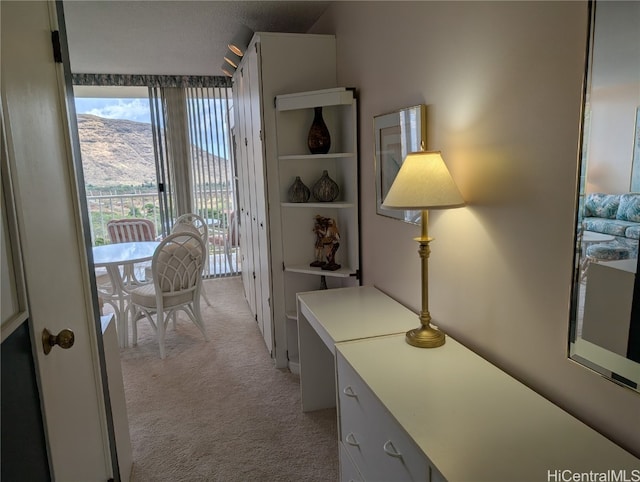 hallway featuring a mountain view and light colored carpet